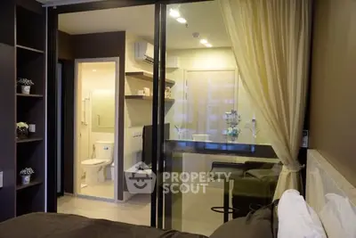 Modern bedroom with glass partition and en-suite bathroom in stylish apartment.