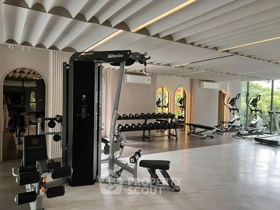 Spacious modern gym with state-of-the-art equipment and large windows for natural light.