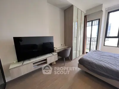 Modern bedroom with sleek TV setup and large window offering natural light.