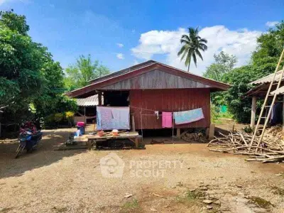 Charming rustic wooden house with lush greenery and open yard, perfect for countryside living.