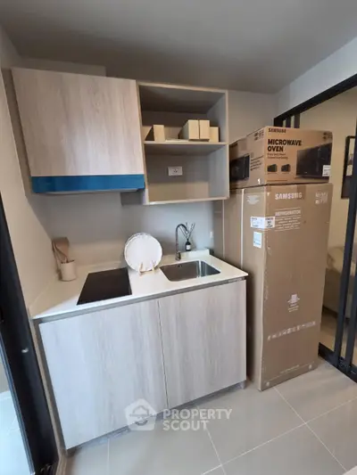Modern compact kitchen with sleek cabinetry and new Samsung microwave oven