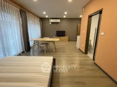 Spacious studio apartment with modern furnishings and large windows for natural light.