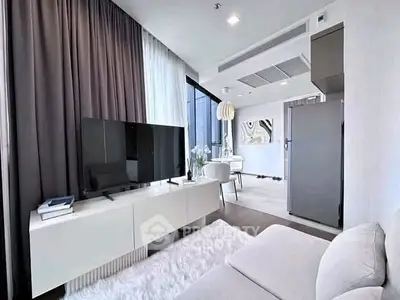 Modern living room with sleek furniture and large TV, featuring open layout and stylish decor.