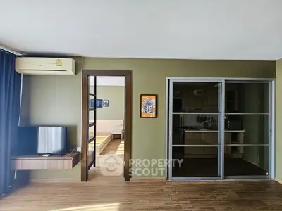 Modern living room with open kitchen and bedroom view, featuring sleek design and wooden flooring.