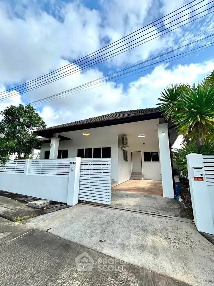 Charming single-story house with modern white facade and gated driveway, perfect for family living.