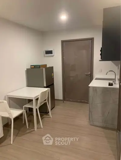 Modern compact kitchen with sleek design and dining area in a cozy apartment.