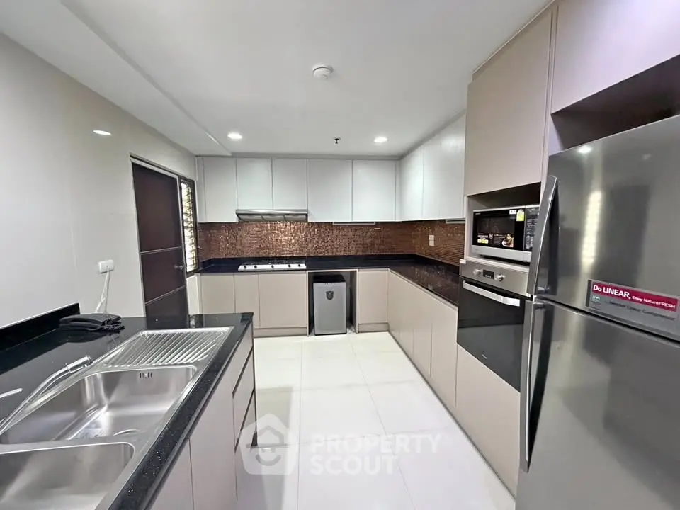 Modern kitchen with sleek cabinetry, stainless steel appliances, and spacious countertops in a contemporary home.