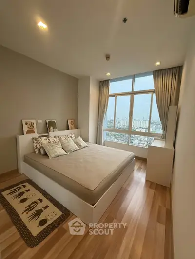 Modern bedroom with large window offering stunning city view, featuring elegant decor and cozy ambiance.