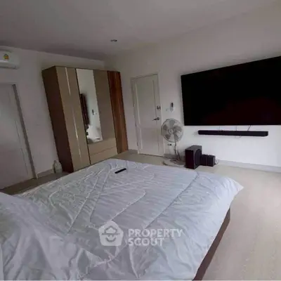 Spacious bedroom with modern decor and large TV for ultimate comfort.
