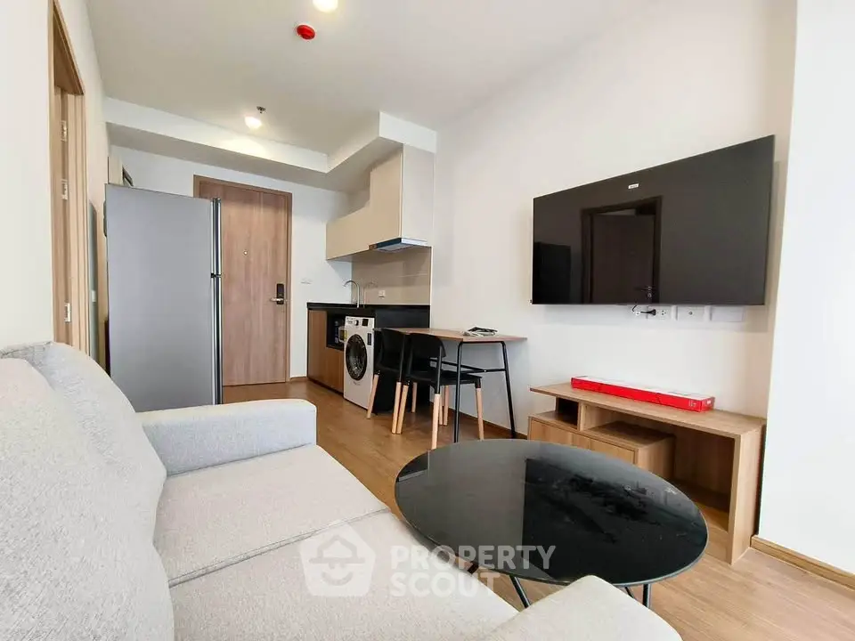 Modern living room with sleek furniture and integrated kitchen appliances in a stylish apartment.