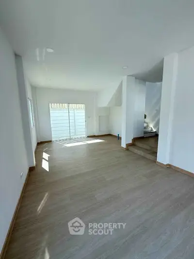Spacious and bright living room with modern wooden flooring and ample natural light.