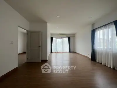 Spacious empty living room with wooden flooring and large windows