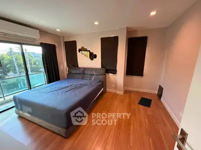 Spacious bedroom with large windows and modern decor, featuring a comfortable bed and wooden flooring.