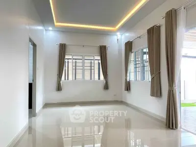 Spacious modern living room with large windows and elegant curtains, featuring sleek tile flooring and ambient lighting.