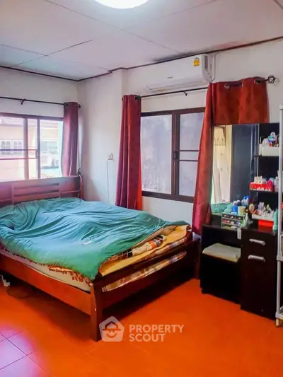 Cozy bedroom with wooden bed and vanity, featuring natural light and warm decor.