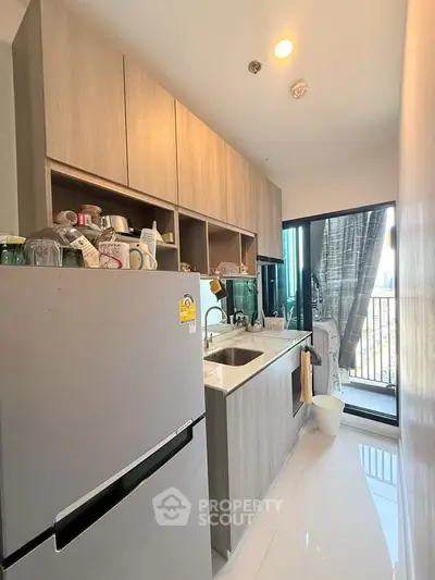 Modern kitchen with sleek cabinetry and balcony view in urban apartment