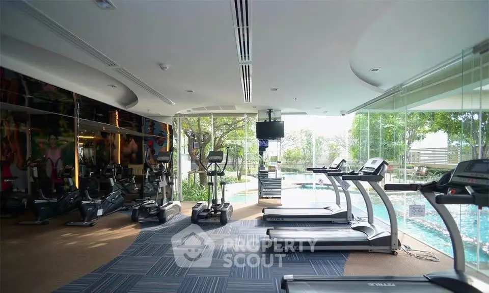 Modern gym with pool view and state-of-the-art equipment in luxury residential complex.