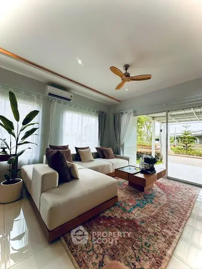 Spacious living room with modern decor, large windows, and garden view, perfect for relaxation and entertaining.