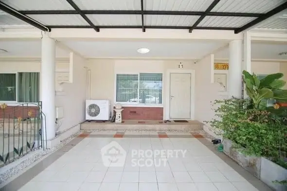 Charming covered entrance with tiled flooring and lush greenery, perfect for welcoming guests.
