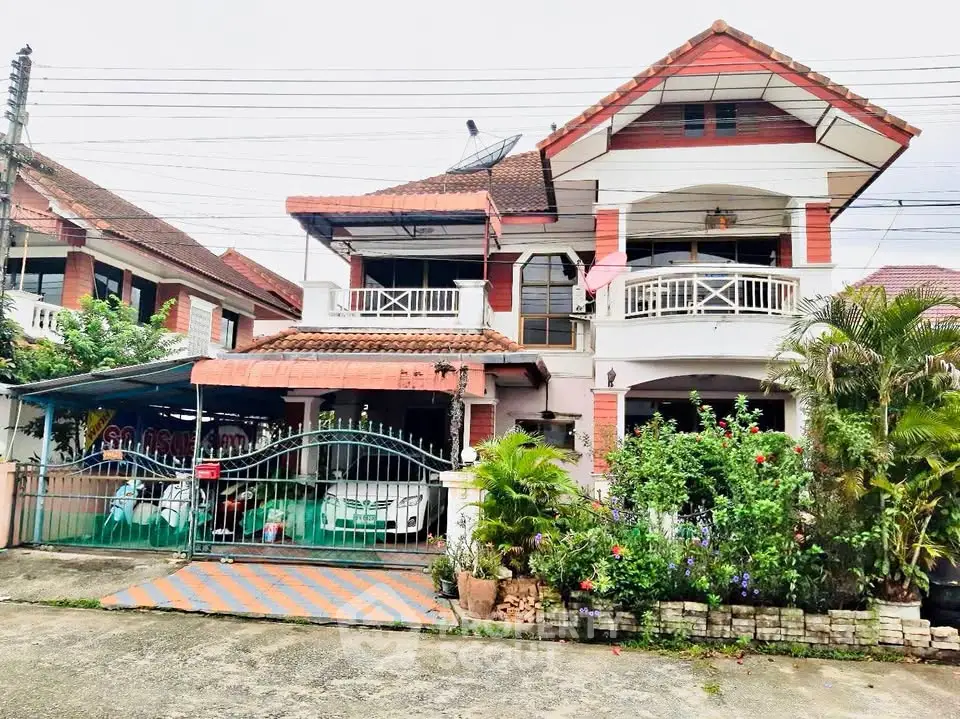 Charming two-story house with balcony and lush garden in a serene neighborhood.