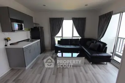 Modern living room with sleek black sofa and stylish kitchen in open layout apartment.