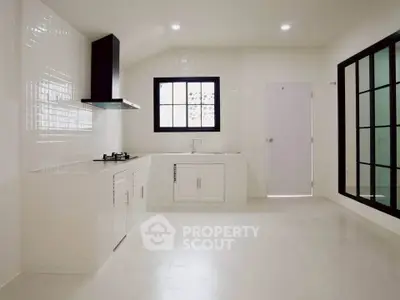Spacious modern kitchen with sleek white cabinetry and gas stove, perfect for culinary enthusiasts.