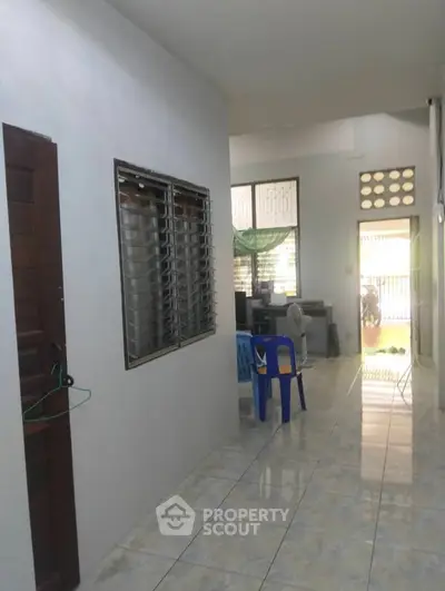 Spacious hallway with tiled flooring and natural light, ideal for versatile living space.