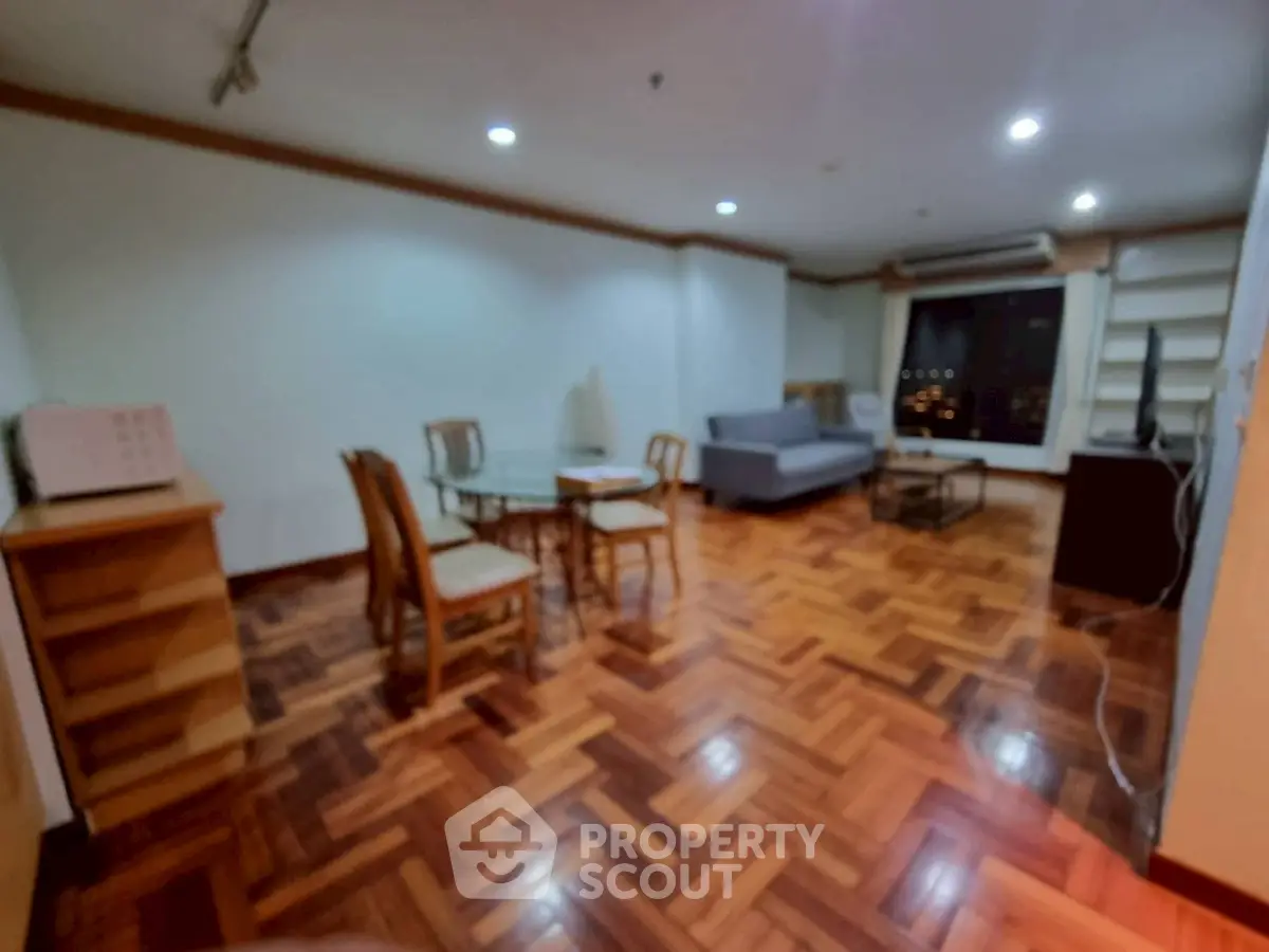 Spacious living room with parquet flooring and modern furniture in a cozy apartment.