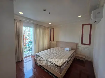 Spacious bedroom with large window and balcony access in modern apartment.
