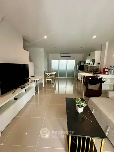 Modern living room with sleek furniture and open layout, featuring a large TV and stylish decor.