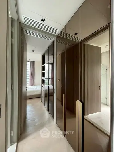 Modern hallway with mirrored closets leading to a cozy bedroom