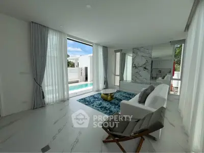 Luxurious living room with pool view, elegant marble accents, and modern furnishings in a bright, airy space.