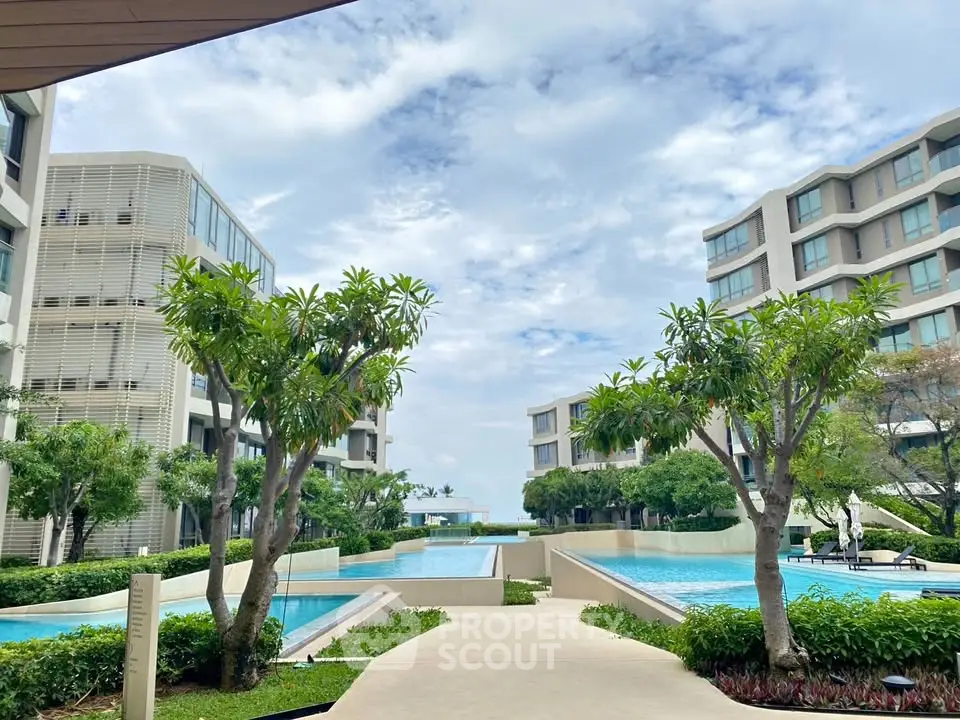 Luxurious modern apartment complex with lush gardens and inviting pools.
