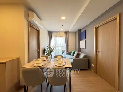 Modern living room with dining area, featuring stylish furniture and natural light.