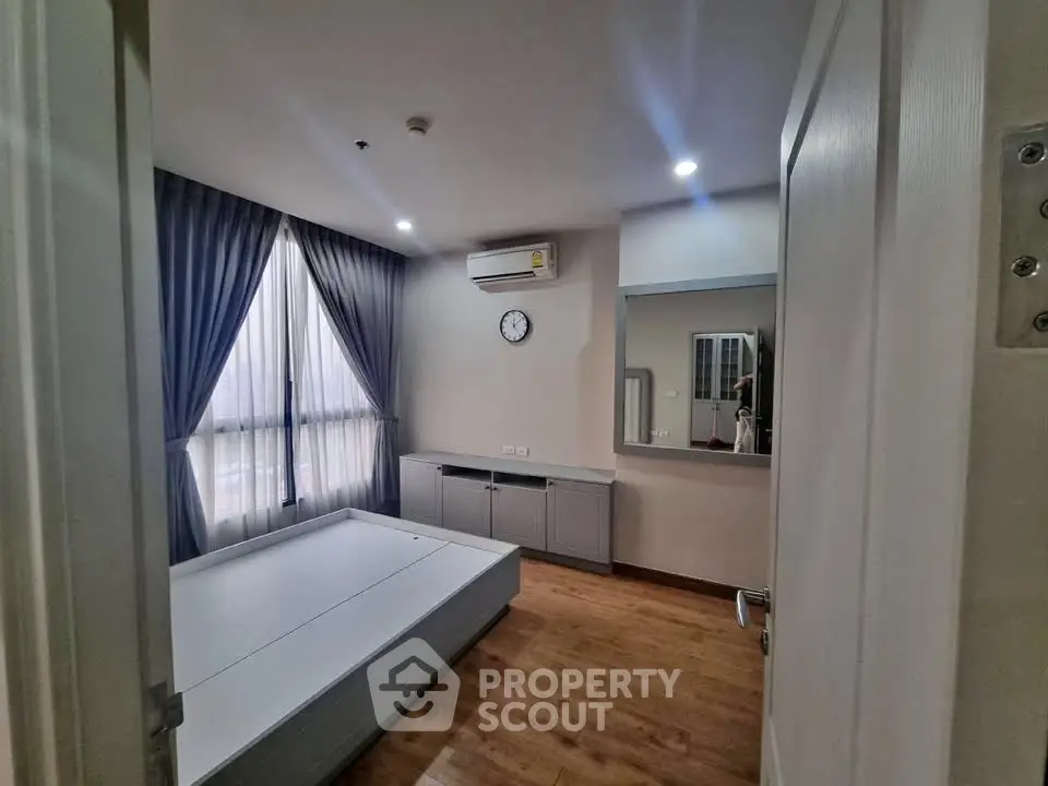Spacious bedroom with modern decor and large window in a stylish apartment.