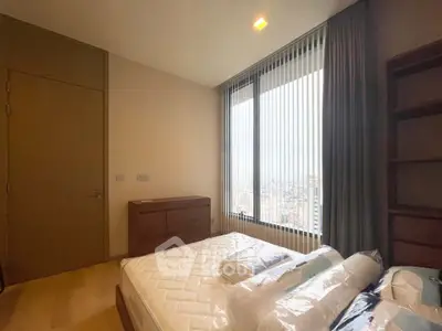 Spacious bedroom with large window offering stunning city views, modern furnishings, and ample natural light.
