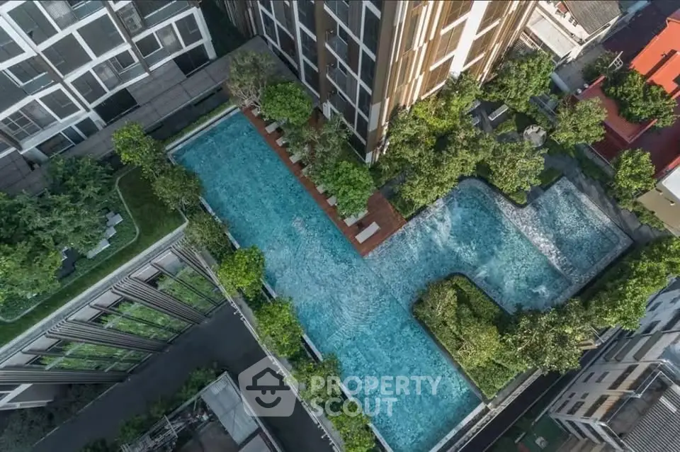Stunning aerial view of luxury apartment complex with expansive pool and lush greenery.