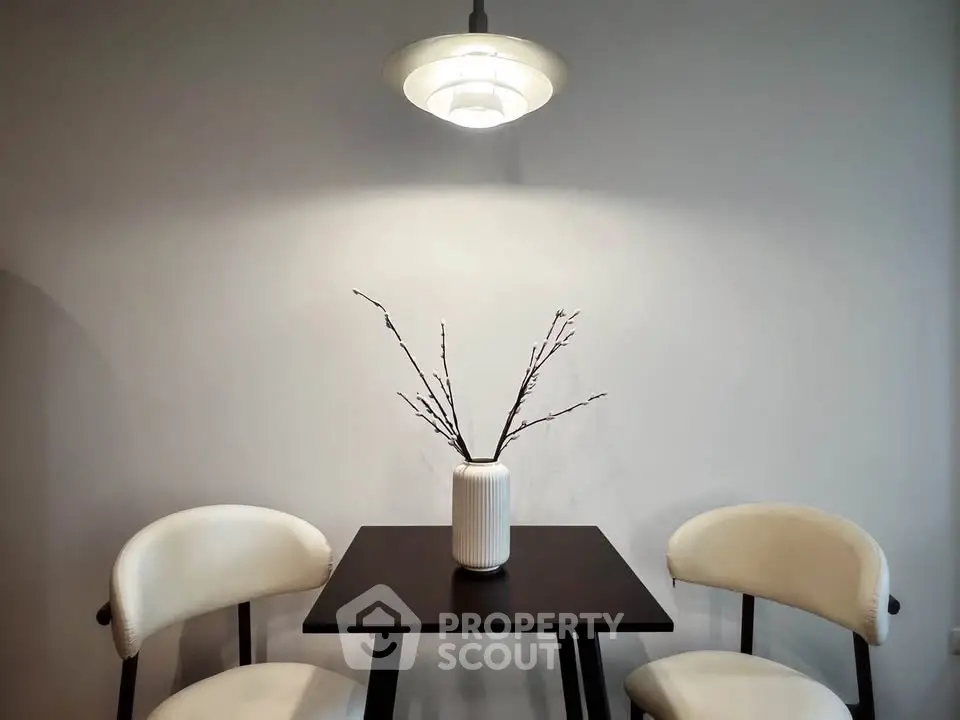 Modern minimalist dining area with sleek table and chairs under elegant lighting.
