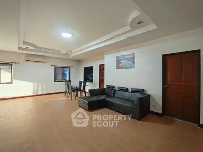 Spacious living room with modern sofa and dining area, featuring elegant ceiling design.