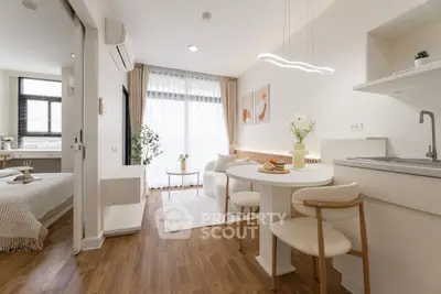 Modern open-plan living room with dining area and cozy bedroom in bright apartment.