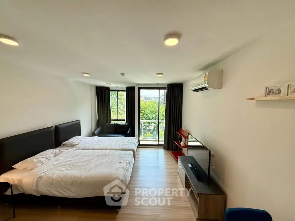 Spacious modern bedroom with twin beds and balcony view in a stylish apartment.