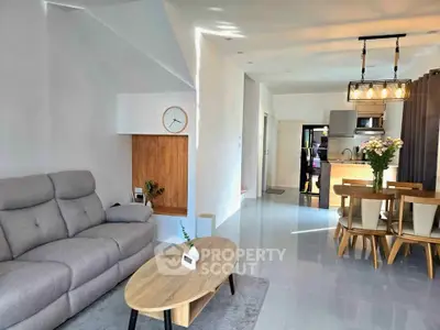 Modern open-plan living room with stylish furniture and dining area, featuring sleek design and natural light.