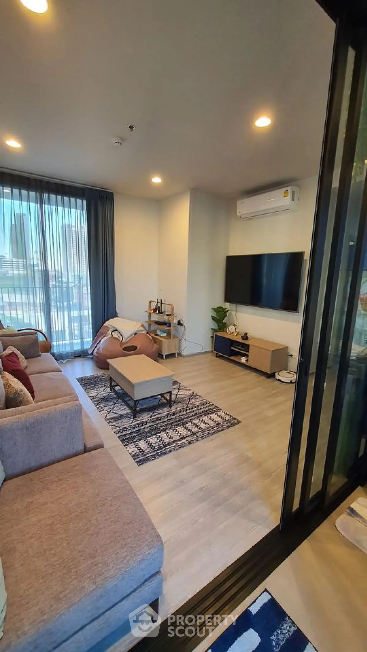 Modern living room with stylish decor, large sofa, and wall-mounted TV in a cozy apartment setting.