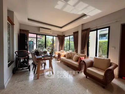 Spacious living room with elegant furniture and large windows offering garden views