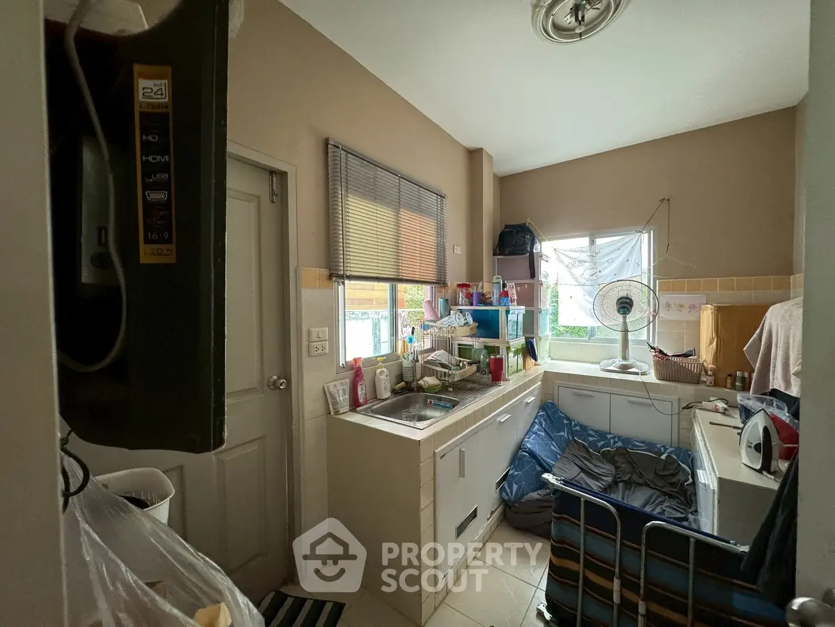 Compact kitchen with cluttered counter and window view