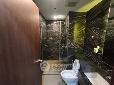 Luxurious modern bathroom with sleek black marble walls and glass shower enclosure.