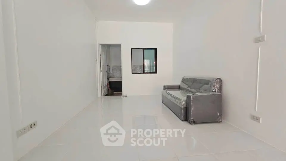 Spacious minimalist living room with sleek tiled flooring and modern sofa, perfect for contemporary living.