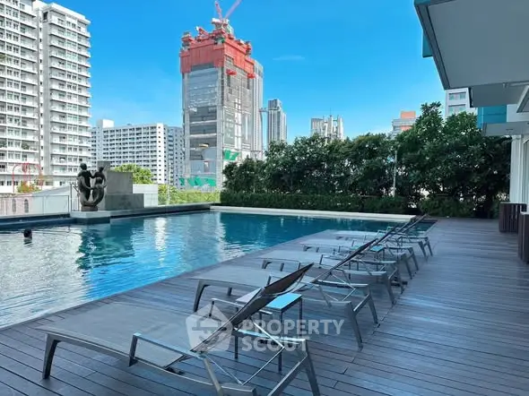 Luxurious rooftop pool with city skyline view and modern lounge chairs, perfect for relaxation.