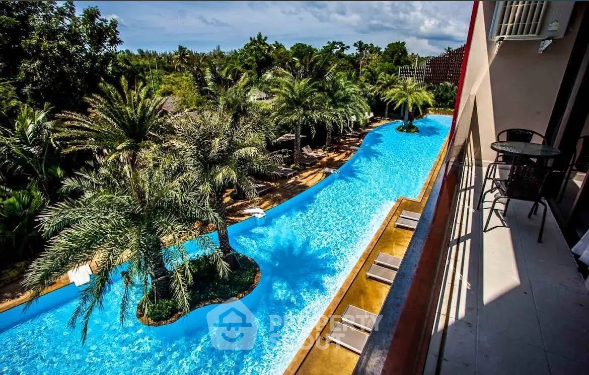 Luxurious resort-style pool view from a private balcony with lush palm trees and serene surroundings.