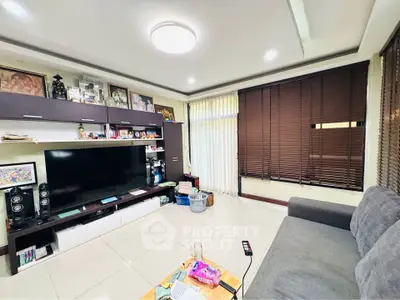Spacious living room with modern decor and large TV, perfect for relaxation.